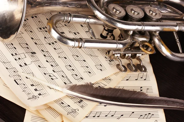 Музыкальные ноты и труба на деревянном столе — стоковое фото