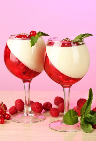 Gelée de fruits avec des baies dans des verres sur table en bois sur fond rose — Photo