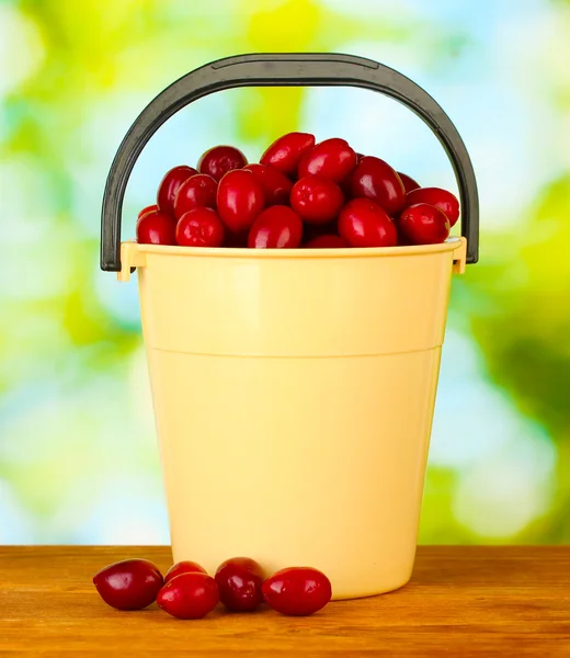 新鲜山茱萸浆果在桶上绿色背景特写 — 图库照片