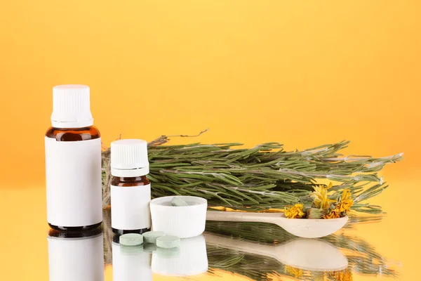 Flaschen mit Medikamenten und Kräutern auf orangefarbenem Hintergrund. Konzept der Homöopathie — Stockfoto