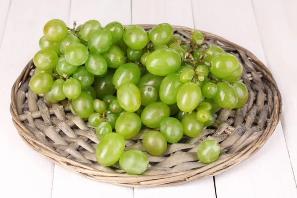 Maturare uva verde primo piano su culla di vimini su tavolo di legno — Foto Stock
