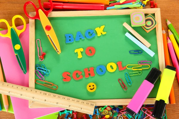 Pequeña pizarra con útiles escolares sobre fondo de madera. Volver a la escuela —  Fotos de Stock