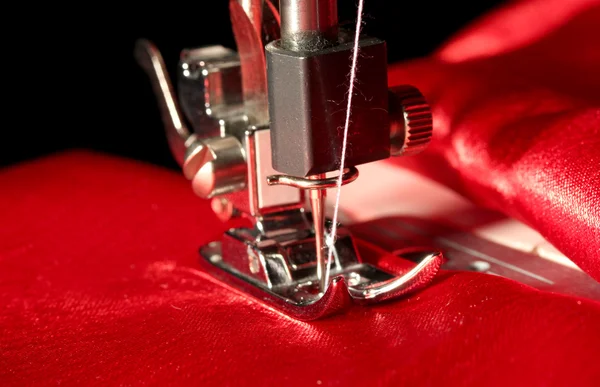 Šicí stroj s červenou látkou closeup — Stock fotografie