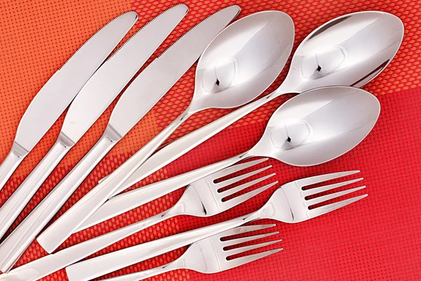 Forks, knifes and spoons on red mat close-up — Stock Photo, Image