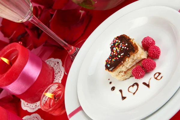 Plate with dessert in form of heart on celebratory table in honor of Valentine's Day close-up — Stock Photo, Image