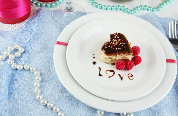 El plato con el postre en forma del corazón a la mesa de fiesta en honor del primer plano del Día de San Valentín —  Fotos de Stock