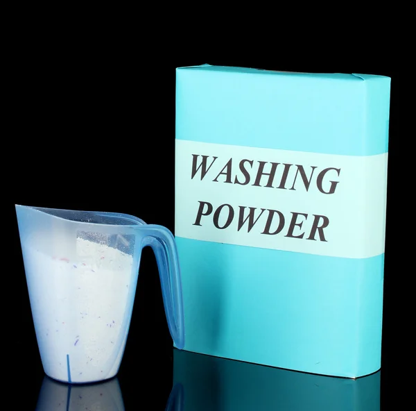Box of washing powder with blue measuring cup, isolated on black — Stock Photo, Image