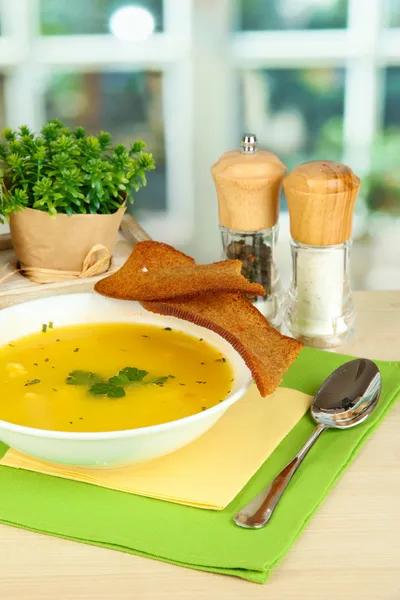 Ароматный суп в белой тарелке на столе на фоне окна крупным планом — стоковое фото