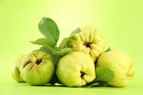 Sweet quinces with leaves, on green background — Stock Photo, Image