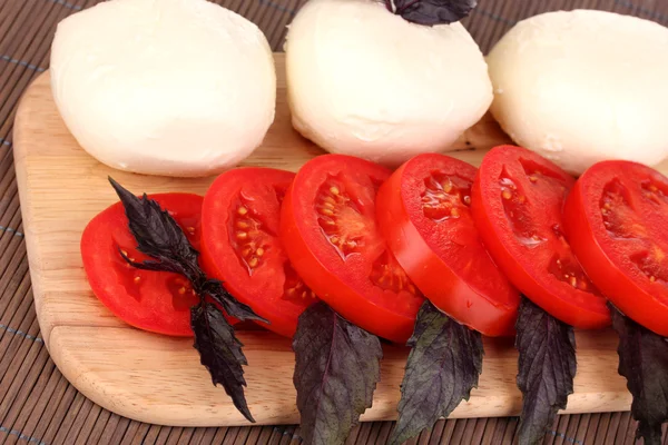 Mozzarella saporita con pomodori sul tagliere primo piano — Foto Stock