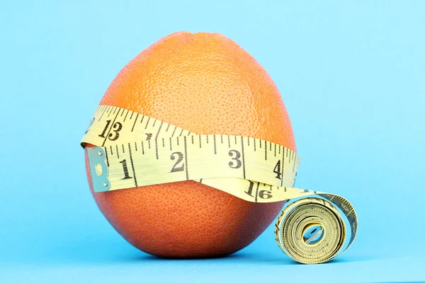 Naranja con cinta métrica sobre fondo azul — Foto de Stock