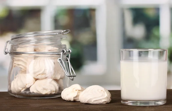 Glas Milch mit Baiser auf Holztisch auf Fensterhintergrund Nahaufnahme — Stockfoto