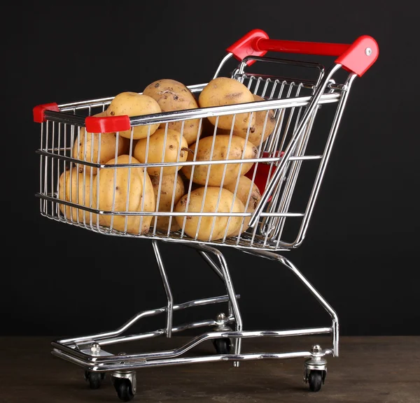 Batatas maduras no carrinho na mesa de madeira no fundo preto — Fotografia de Stock