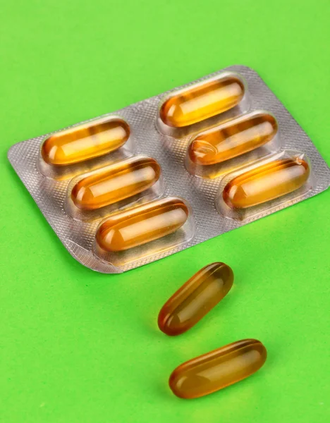Capsules packed in blister on green background — Stock Photo, Image