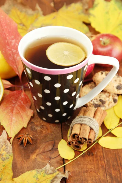 Xícara de chá quente e folhas de outono, em fundo de madeira — Fotografia de Stock