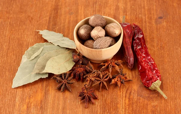 Nutmeg and other spices on wooden background — Stock Photo, Image