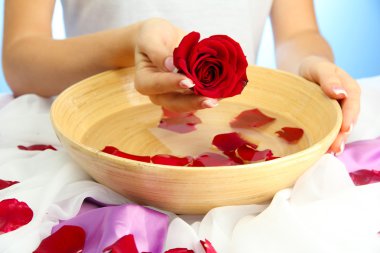 kadın eliyle su yaprakları, mavi zemin üzerine ahşap kase