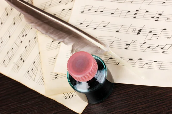 Музичні ноти і перо на дерев'яному столі — стокове фото