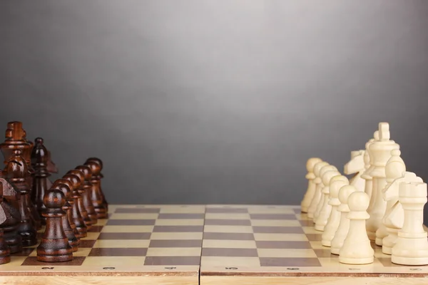 Chess board with chess pieces on grey background — Stock Photo, Image