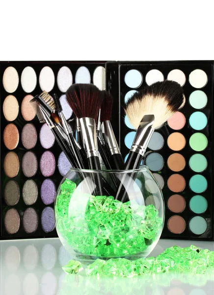 Make-up brushes in a bowl with stones on palette of shadows background — Stock Photo, Image