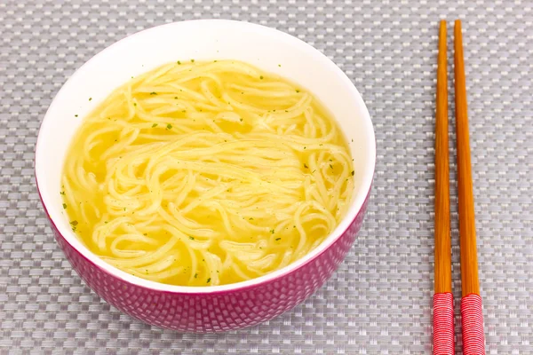 Fideos asiáticos en tazón en estera gris —  Fotos de Stock