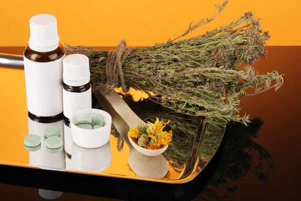 Lahve léků a bylin na oranžovém pozadí. koncepce homeopatie — Stock fotografie