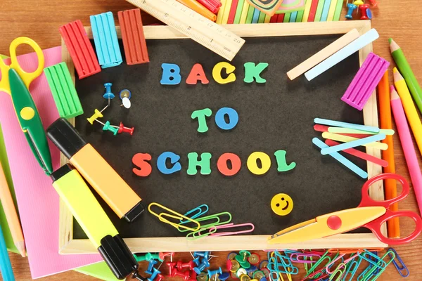 Small chalkboard with school supplies on wooden background. Back to School — Stock Photo, Image
