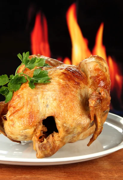Roasted whole chicken on a white plate on wooden background close-up — Stock Photo, Image
