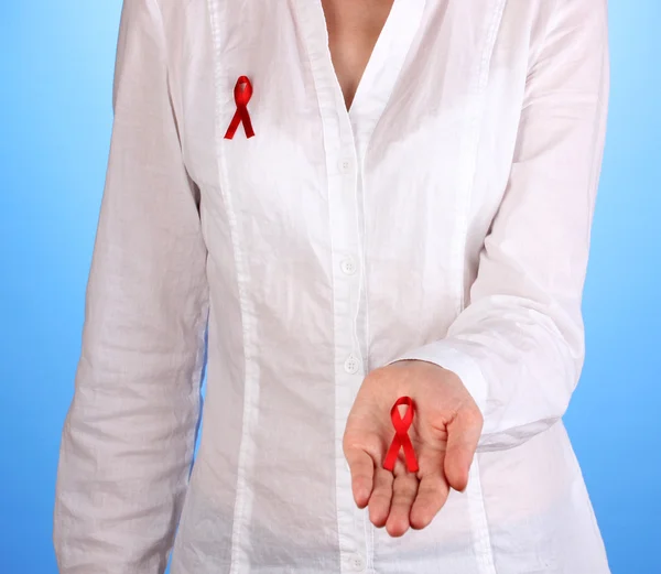Woman with red ribbon in hands on blue background — Stock Photo, Image