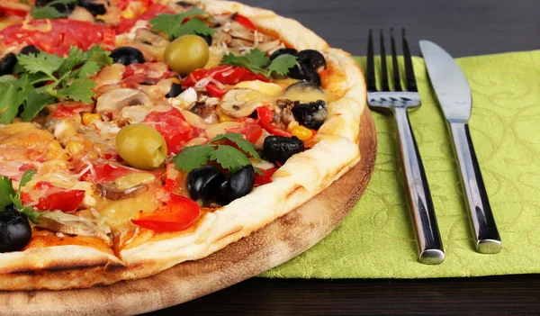 Delicious pizza close-up on wooden table on room background — Stock Photo, Image