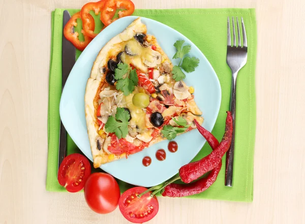 Delicious slice of pizza on color plate with ingredients around close-up on wooden table — Stock Photo, Image
