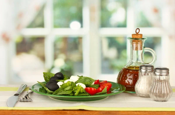 Käse-Mozzarella mit Gemüse auf dem Teller mit Gabel und Messer auf Holztisch — Stockfoto