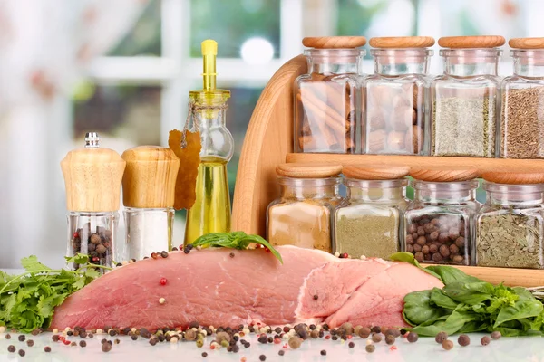 Um grande pedaço de porco marinado com ervas, especiarias e óleo de cozinha na mesa branca no fundo da janela — Fotografia de Stock