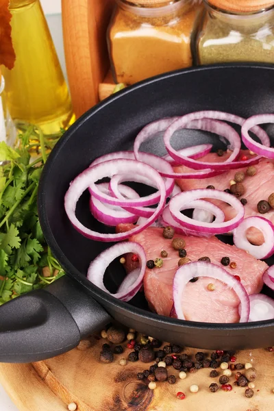 Un morceau de porc avec des oignons frits dans une poêle avec des herbes, des épices et de l'huile de cuisson à bord close-up — Photo