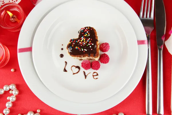 El plato con el postre en forma del corazón a la mesa de fiesta en honor del primer plano del Día de San Valentín —  Fotos de Stock