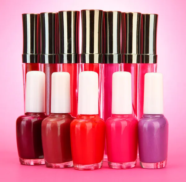 Beautiful lip glosses and nail polish bottles, on pink background — Stock Photo, Image