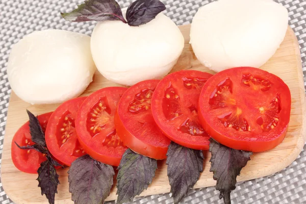 Tasty mozzarella with tomatoes on chopping board close-up — Stock Photo, Image