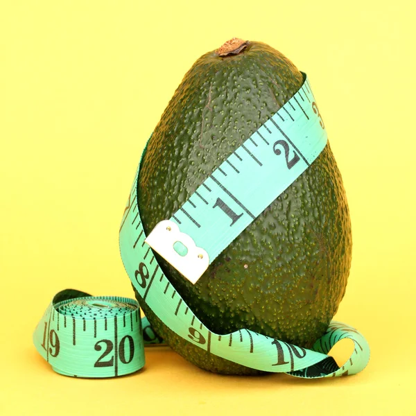 Avocado mit Maßband auf gelbem Hintergrund — Stockfoto