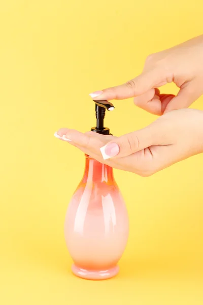 Woman squeezing lotion on her hand, on yellow background close-up — Stock Photo, Image