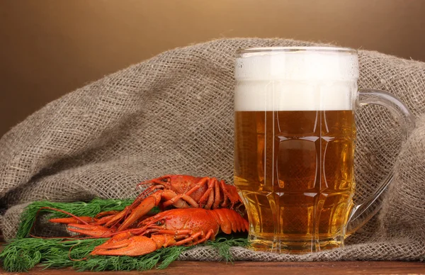Leckere gekochte Krebse und Bier auf dem Tisch vor braunem Hintergrund — Stockfoto