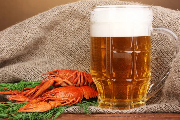 Smakelijke gekookte rivierkreeftjes en bier op tafel op bruine achtergrond — Stockfoto