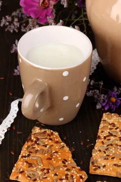 Krug und Tasse Milch mit Keksen auf Holztisch in Großaufnahme — Stockfoto