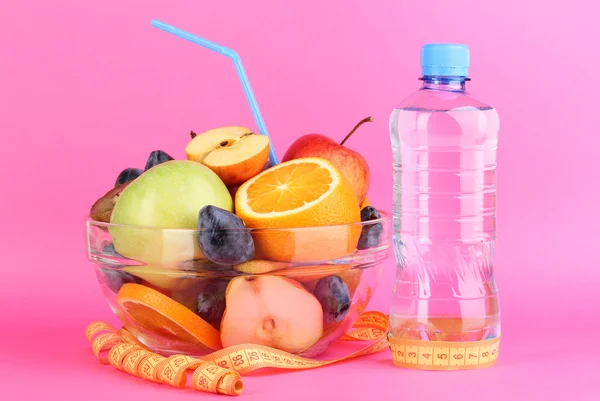 玻璃碗水果饮食，测量磁带和粉红色的背景上瓶水 — 图库照片