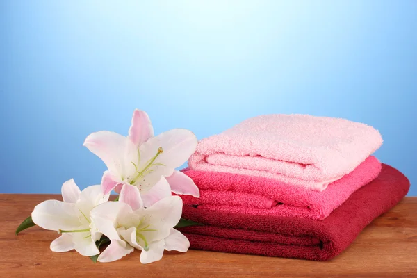 Pila de toallas con lirio rosa sobre fondo azul —  Fotos de Stock