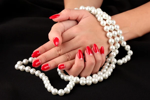 Weibliche Hände mit Perlen auf farbigem Hintergrund — Stockfoto
