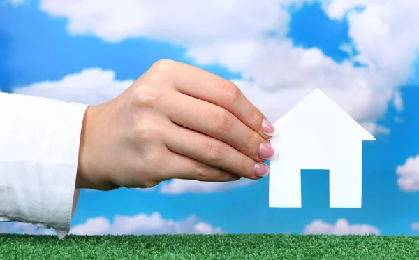 Concept : main de femme avec maison en papier sur fond de ciel, gros plan — Photo