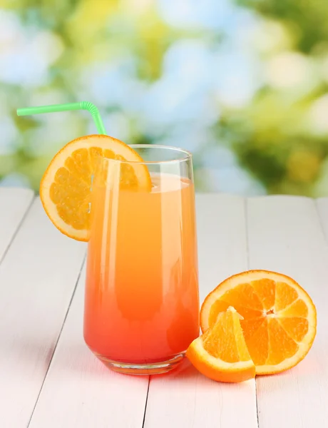 Glass of multicolor cocktail on wooden table on bright background — Stock Photo, Image