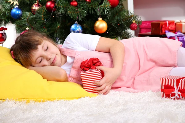 La niña se quedó dormida con el regalo en sus manos en la habitación festivamente decorada — Foto de Stock