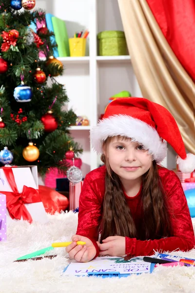 Beautiful little girl writes letter to Santa Claus in festively decorated room — Stock Photo, Image