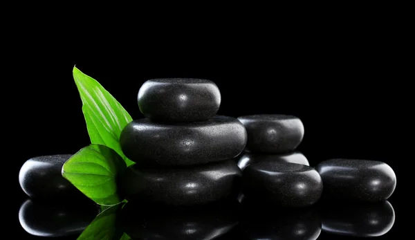 Wellness-Steine und grüne Blätter auf schwarzem Hintergrund — Stockfoto